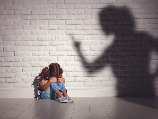 Mädchen vor Wand und Schatten einer Frau mit erhobenem Finger