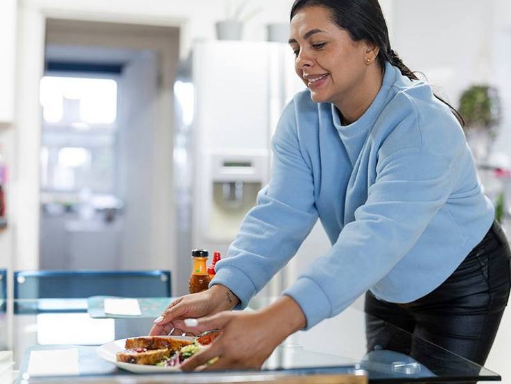 Frau, die einen gefüllten Teller auf dem Tisch platziert - AWO KV Breisgau-Hochschwarzwald/Emmendingen e.V.
