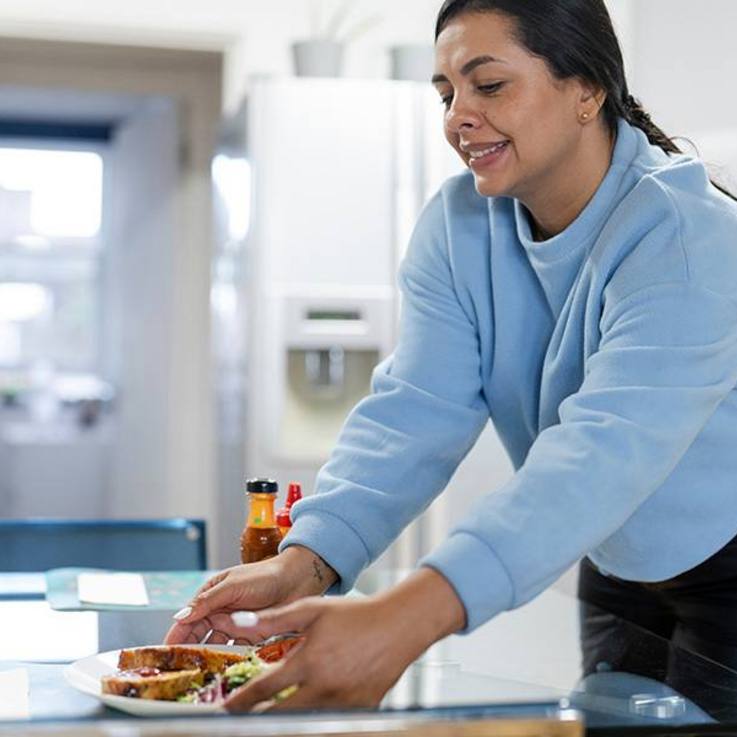 Frau, die einen gefüllten Teller auf dem Tisch platziert - AWO KV Breisgau-Hochschwarzwald/Emmendingen e.V.