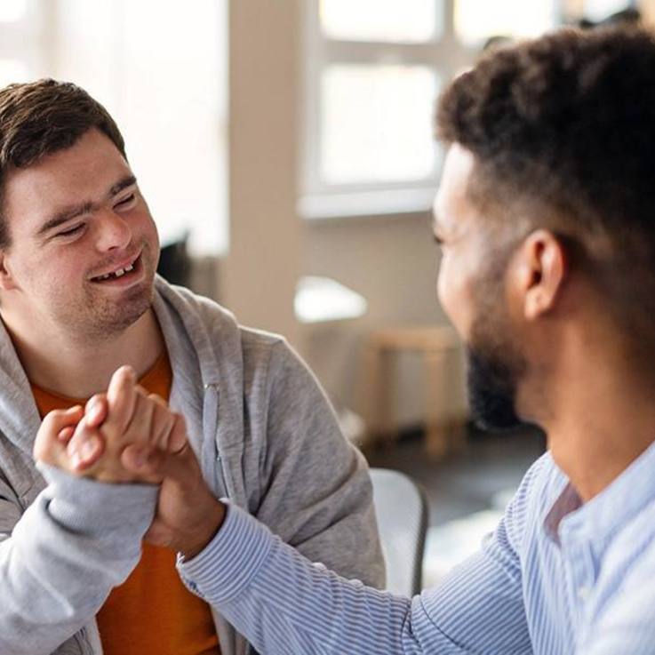 Handschlag zweier junger Männer - CARITIVA fördert Inklusion