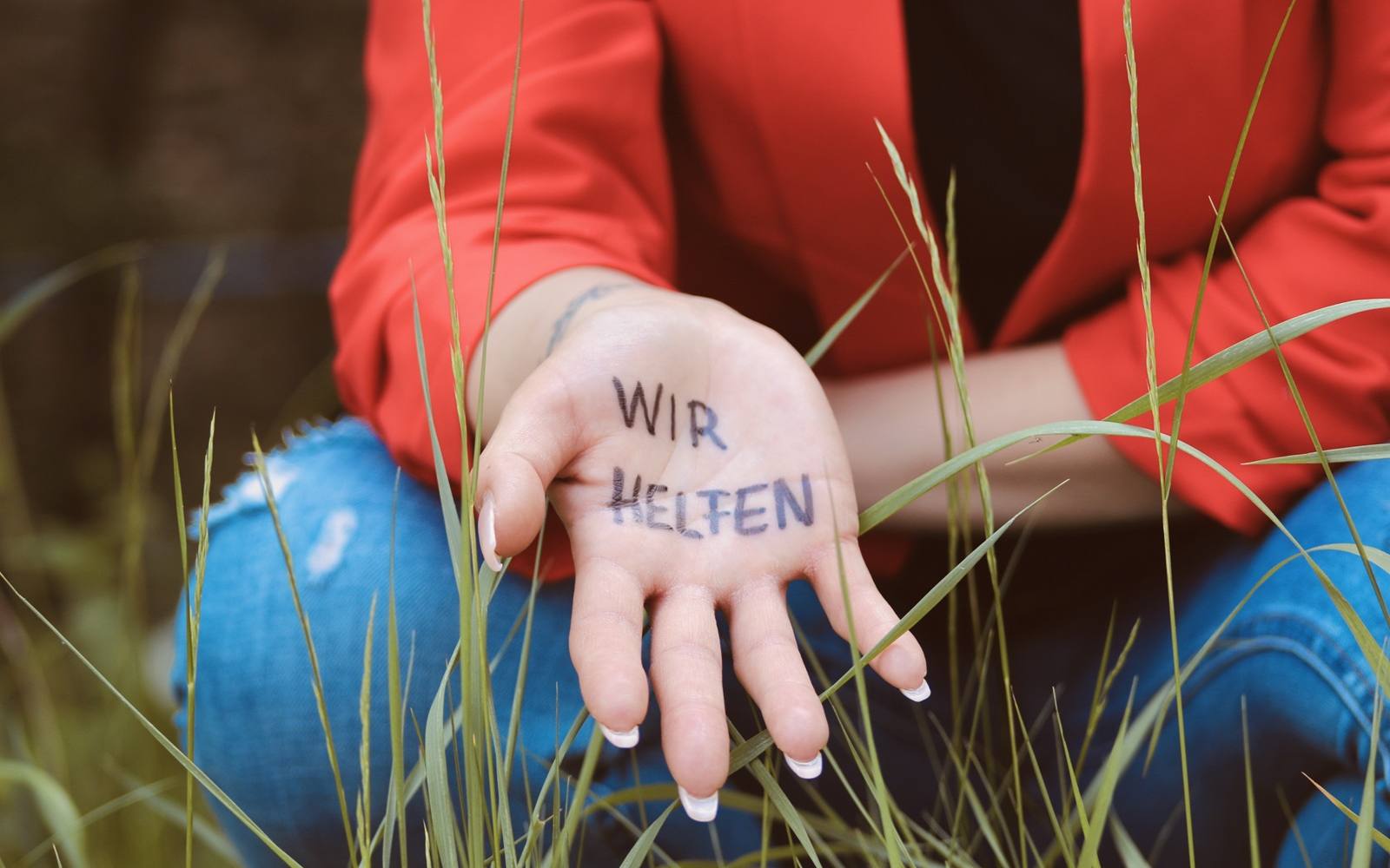 wir helfen auf handflaeche geschrieben