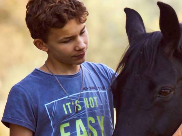Junge und Pferd - einander zugewandt - auf dem Gelände der Paulihof Kinderhilfe gGmbH in Kühbach/Unterbernbach