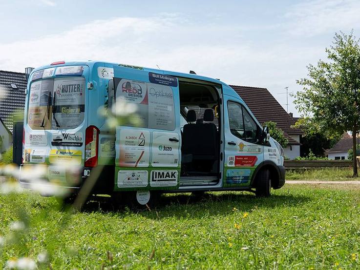 Der folierte Ford Transit Kombi für die Paulihof Kinderhilfe gGmbH auf der Wiese - die Seitentür ist geöffnet