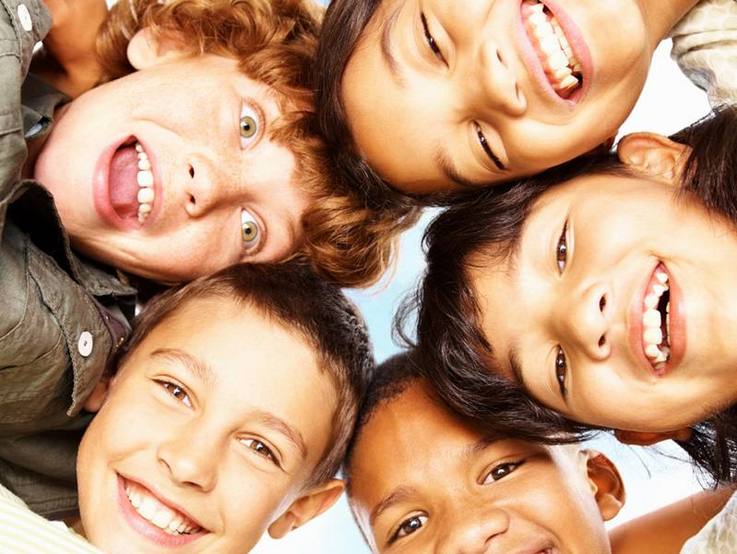 Sechs Kinder lächeln Kopf an Kopf in die Kamera hinunter