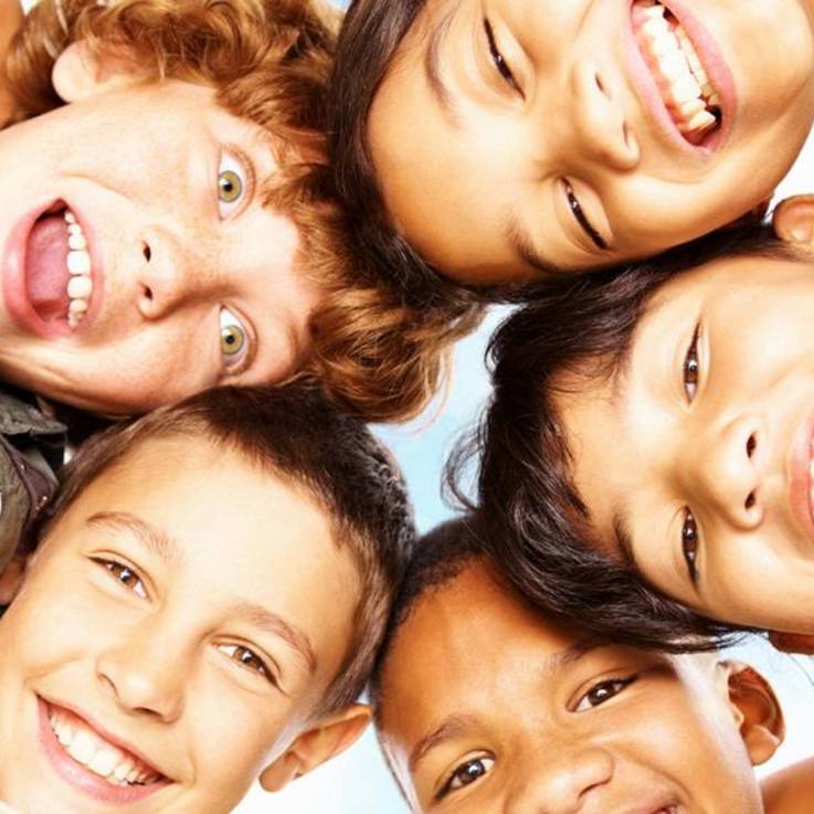 Sechs Kinder lächeln Kopf an Kopf in die Kamera hinunter