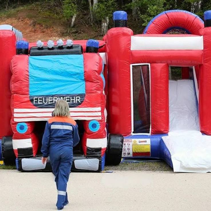 Ein Kind in Jugendfeuerwehr-Kleidung geht auf die Feuerwehr-Hüpfburg zu