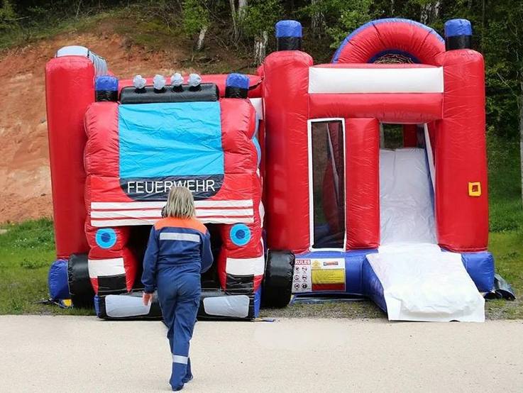 Ein Kind in Jugendfeuerwehr-Kleidung geht auf die Feuerwehr-Hüpfburg zu