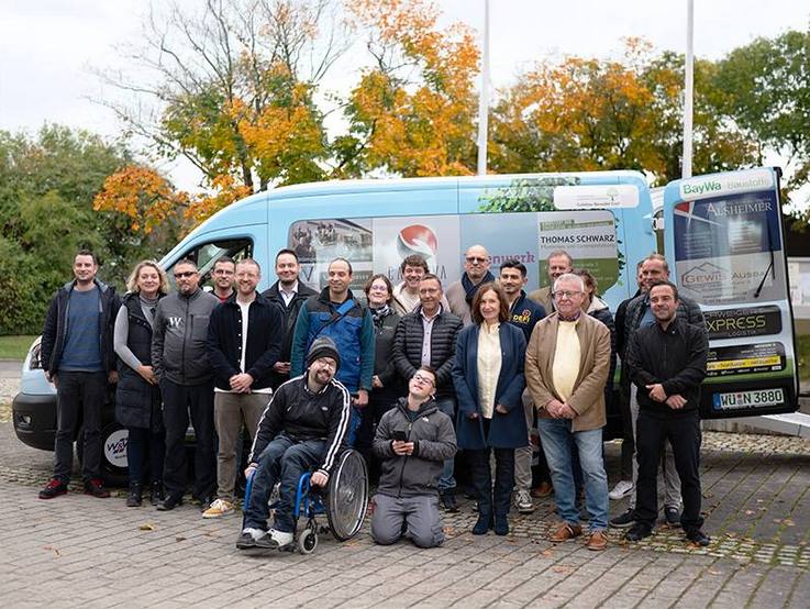 Tatenwerk (St. Josefs-Stift Eisingen gGmbH) folierter gesponsorter Ford Transit fahrerseitig mit Team davor