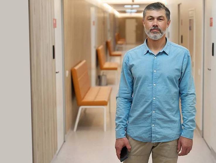 Mann im Krankenhausflur mit Mobiltelefon in der Hand