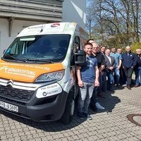 belegschaft steht vor gesponsortem fahrzeug