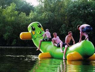 vier jungen auf eine aufblasbaren wurm im see